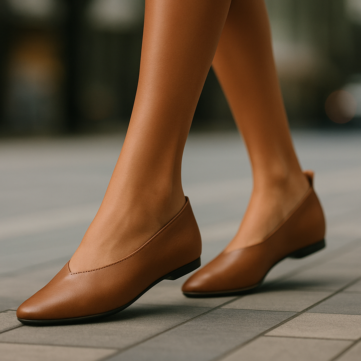 Brown leather shoes worn on a blurred outdoor background