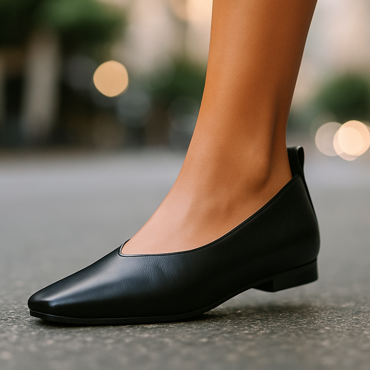 Black flat shoe worn on a blurred street background